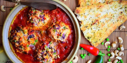 Baked mushrooms stuffed with ricotta, cashews and peas in a spicy tomato sauce, served with garlic naan
