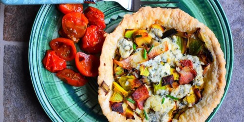 A starter of leek and blue cheese tartlet with roasted tomatoes